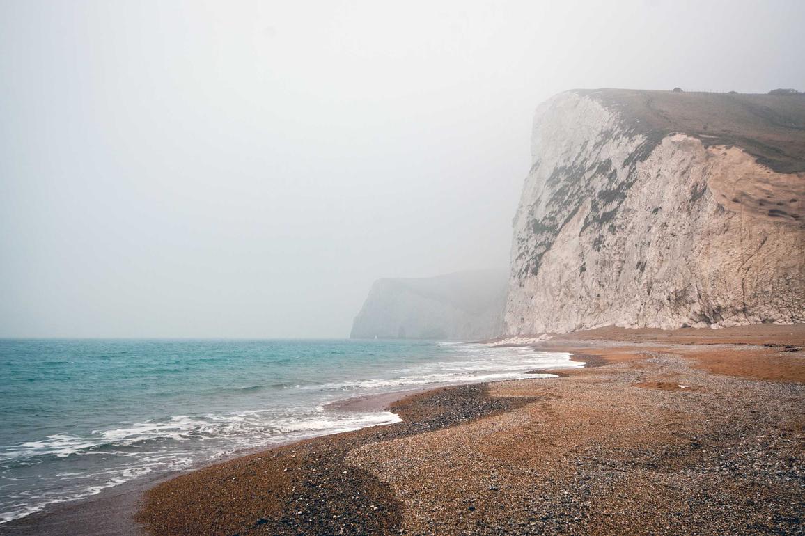 Natuurfoto van kliffen aan de kust met mist en zee, geschikt voor toegankelijkheid en natuurbeleving.
