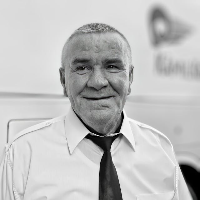 Een oudere man in uniform met een vriendelijke glimlach, geschikt voor toegankelijkheid en inclusie.